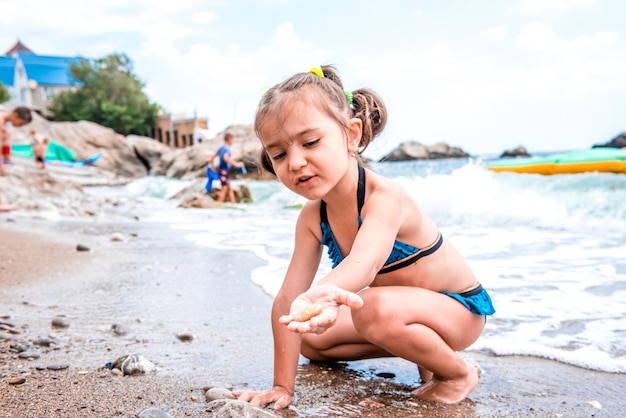 Kleines süßes fröhliches Mädchen in einem blauen Badeanzug am Meer Porträt eines Mädchens Kindertourismus