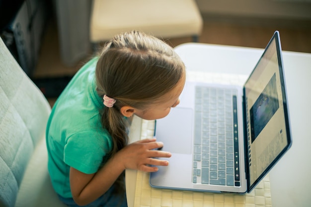 Kleines süßes Mädchen benutzt Laptop, um Videoanrufe zu führen