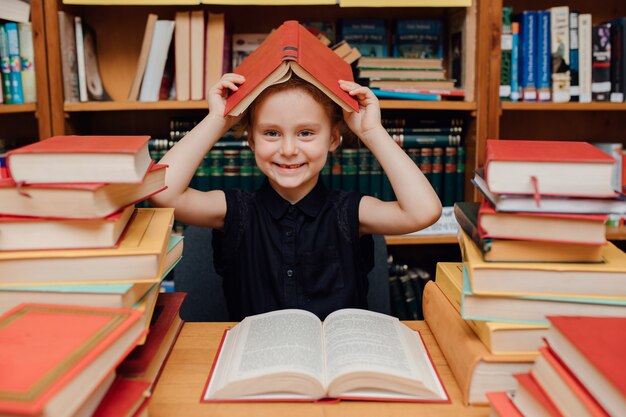 Kleines süßes Mädchen, das in der Bibliothek liest