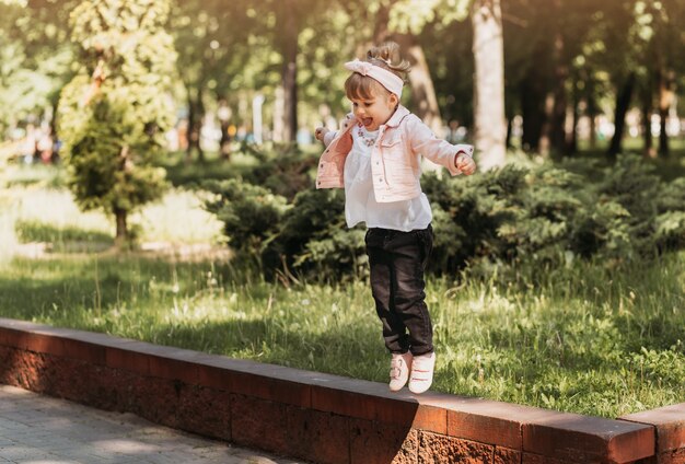 Kleines süßes Mädchen, das Spaß hat und im Sommer im Park spielt