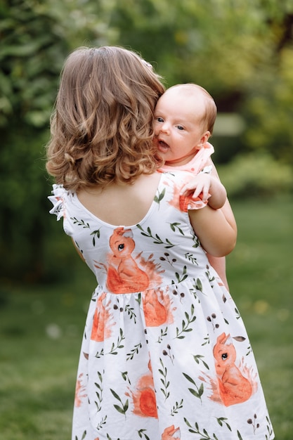 Kleines süßes Mädchen hält eine neugeborene Schwester in ihren Armen und verbringt glückliche Zeit mit ihr draußen