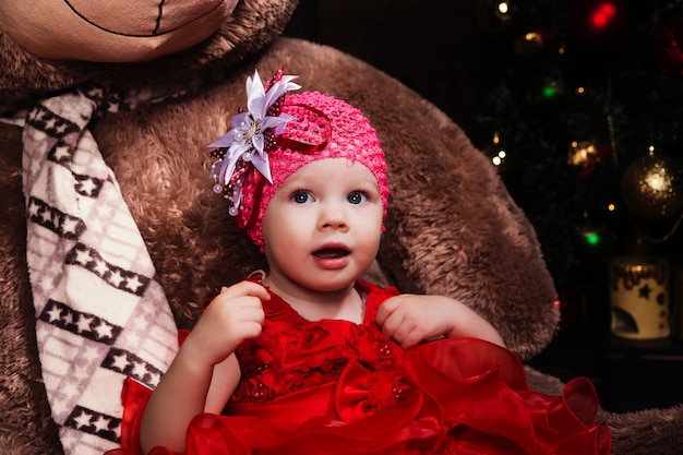 Kleines süßes Mädchen im roten Kleid mit großem Teddybär