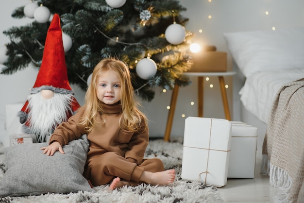 Kleines süßes Mädchen in der Nähe von Weihnachtsbaum