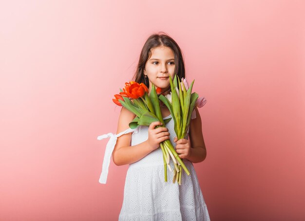 Kleines süßes Mädchen mit einem Strauß Tulpen auf rosa Hintergrund Fröhlicher Frauentag Platz für Text Lebhafte Emotionen 8. März