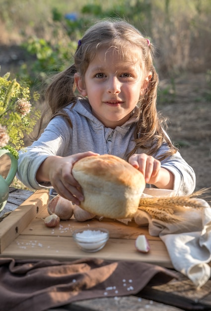 Kleines süßes Mädchen mit einem Tablett mit frischem Brot und Knoblauch