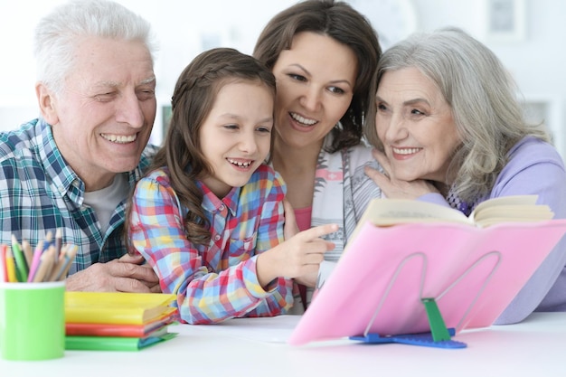 Kleines süßes Mädchen mit Großeltern, die zu Hause lernen