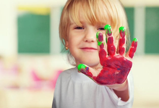 Kleines süßes Mädchen mit Hand in farbiger Farbe