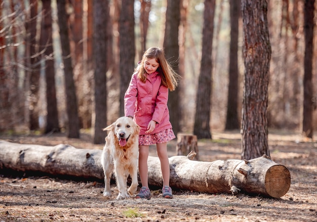 Kleines süßes Mädchen und Golden Retriever Hund beim Frühlingsspaziergang im Wald