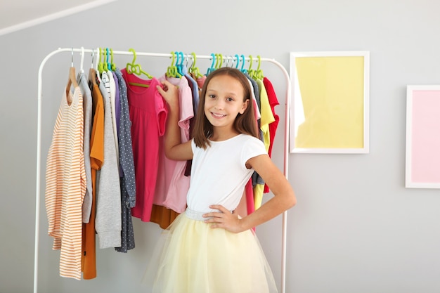 Kleines süßes Mädchen wählt Kleidung in der Umkleidekabine