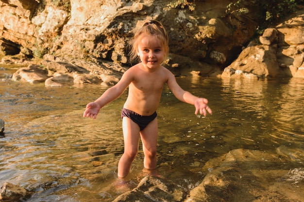 Kleines süßes schönes Mädchen schwimmt in einem Gebirgsfluss