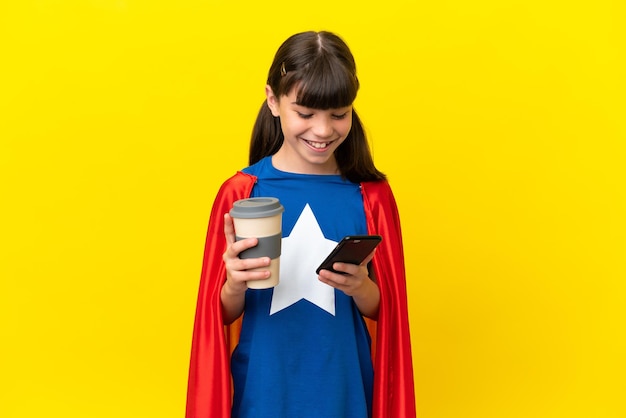 Kleines Superheldenkind isoliert auf violettem Hintergrund, das Kaffee zum Mitnehmen und ein Handy hält