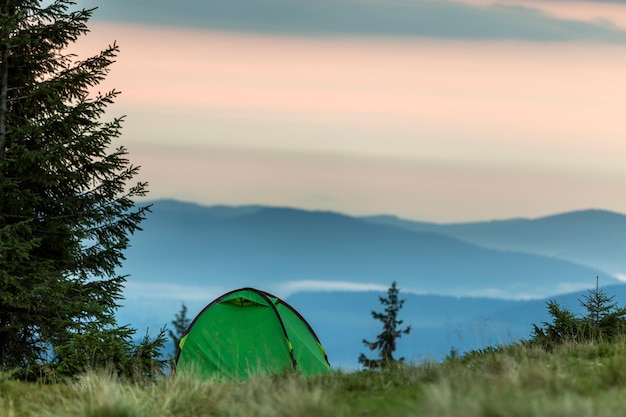 Foto kleines touristisches zelt auf grasartigem gebirgshügel. sommercamping in den bergen im morgengrauen. tourismus-konzept.