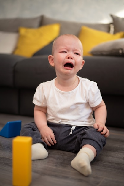 Kleines unglückliches Kind, das auf dem Boden in seinem Zimmer weint