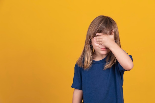 Kleines vergessenes Mädchen bedeckt ihr Gesicht mit ihren Händen