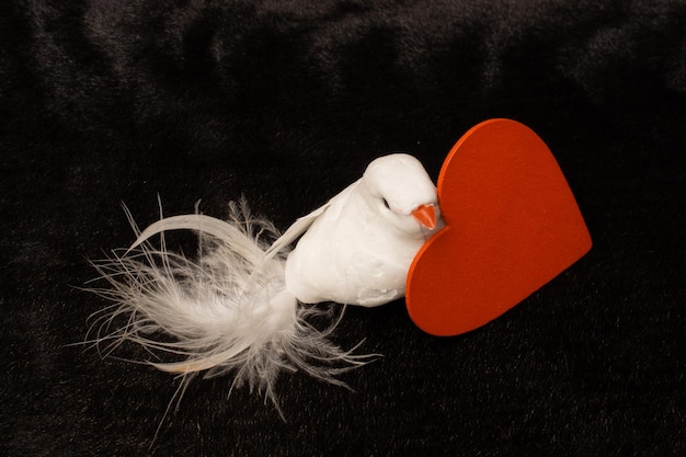 Kleines Vogelmodell mit Herzsymbol in seinem Schnabel als Valentinstag