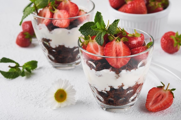 Kleinigkeiten Brownies frische Erdbeer- und Mascarpone-Creme serviert in Schichten auf Glas auf weißem Hintergrund Portion Desserts Kein gebackener Brownie-Käsekuchen mit frischen Beeren in einem Glas