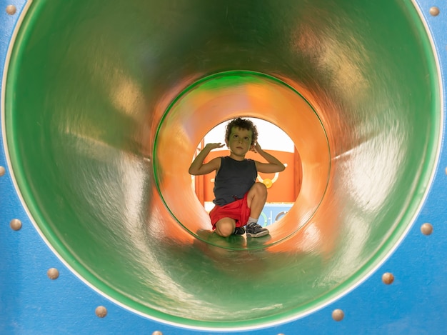 Kleinkind am Eingang einer Röhre in einem Spielplatzspiel
