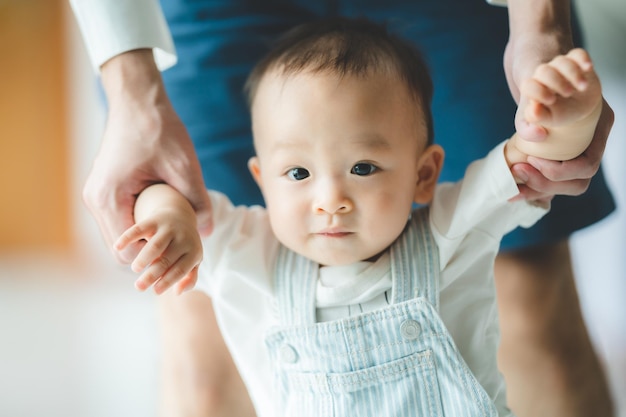 Kleinkind Baby laufen lernen und Unterstützung durch die Familie zusammen haben kleines Kind mit Vater und Mutter zu Hause mit dem ersten Schritt zum Gehen mit Hilfe und Händchenhalten von Papa glückliche Kindheit Hilfe Pflege