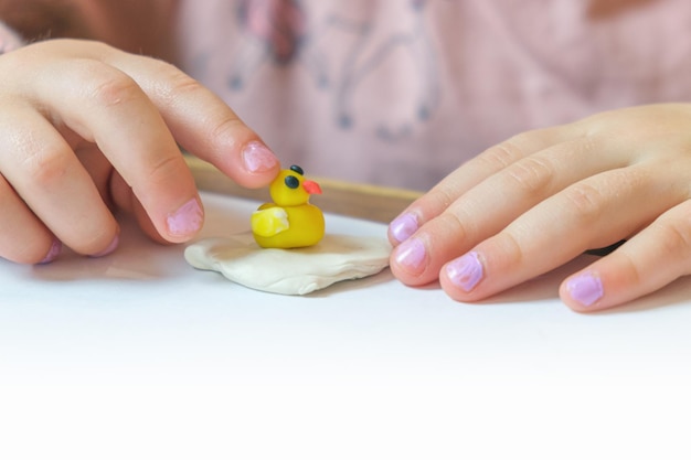 Kleinkind formt aus farbigem Plastilin auf weißem Tisch