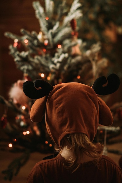 Foto kleinkind in rudolph-rentierkostümen schmückt weihnachtsbaum weihnachtsbaum