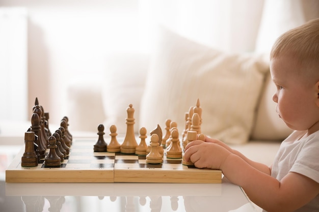 Kleinkind Junge spielt Schach im Zimmer Kleines cleveres Kind, das zu Hause Schach spielt Bildungskonzept