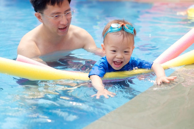 Kleinkind-Jungenkind, das lernt, mit Poolnudel zu schwimmen