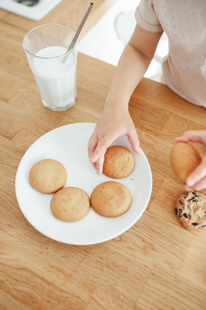 Kleinkind Mädchen trinkt Milch mit Stahlstroh aus Glas und isst Kekse Nachhaltiges Leben mit Kindern