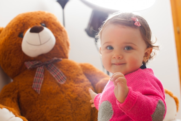 Kleinkindbaby, das mit großem Teddybären spielt