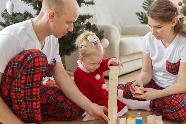 Kleinkinder mit Cochlea-Implantat spielen mit Eltern unter Weihnachtsbaumtaubheit und innovativen medizinischen Technologien für Hörgeräte und Vielfalt