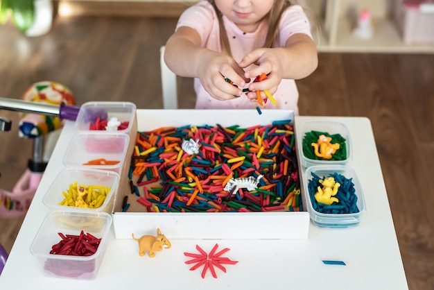 Kleinkinder spielen mit sensorischen Behältern mit farbig gefärbten Nudeln Sensorisches Spielen und Lernen von Farben für Kinderaktivitäten Montessori-Spiele für feinmotorische handwerkliche Aktivitäten