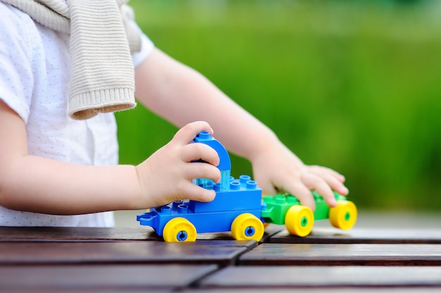 Kleinkindjunge, der draußen mit spielzeugzug am warmen sommertag spielt