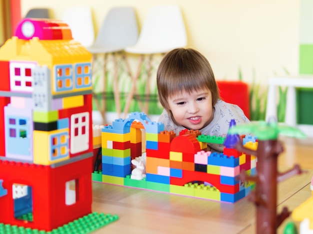 Kleinkindjunge spielt im kidsroom mit buntem Erbauer