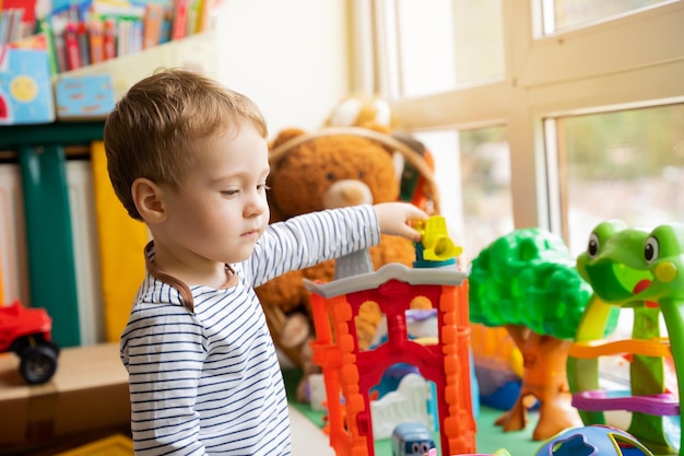 Kleinkindjunge spielt mit Spielzeug im Kinderzimmer Lernspielzeug für Kleinkinder Kind eineinhalb Jahre zwei Jahre Selektiver Fokus