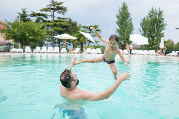 Kleinkindkinderkind, das im Swimmingpool hat Spaßfreizeitaktivität spritzt