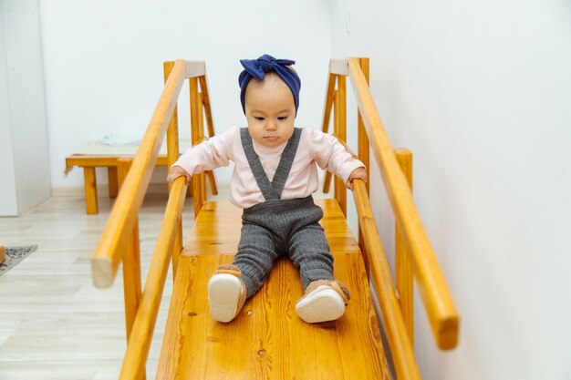 Kleinkindmädchen, das auf einer Holzrutsche für Kinder reitet