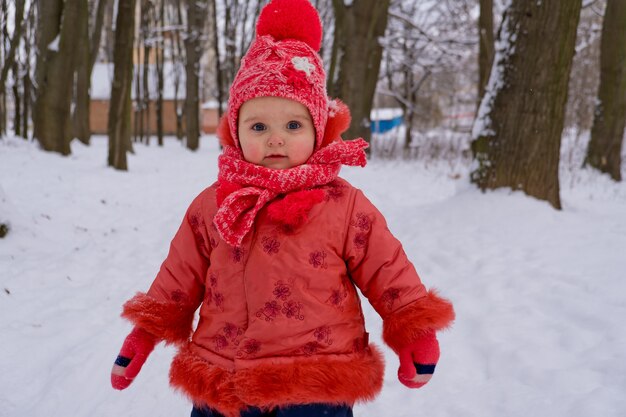 Kleinkindmädchen, das durch Schnee im Park geht. Frost Wintersaison.