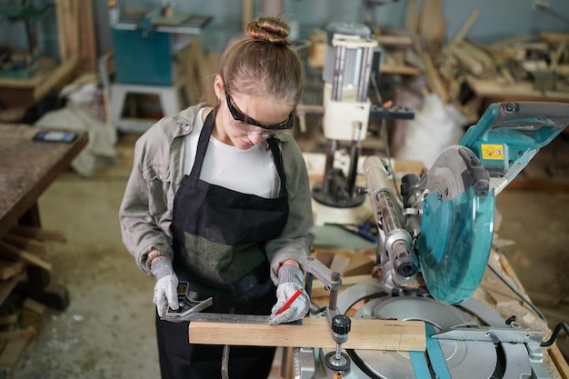 Kleinunternehmen einer jungen Frau Schöne junge Arbeitnehmerin in einem Möbelwerkraum, der Holz misst