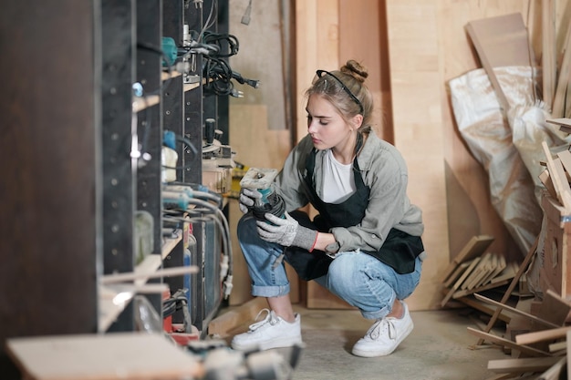 Kleinunternehmen einer jungen Frau Schöne junge Arbeitnehmerin in einem Möbelwerkraum, der Holz misst