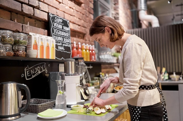 Kleinunternehmen, Menschen und Servicekonzept - glückliche Frau oder Bardame, die im veganen Café kocht