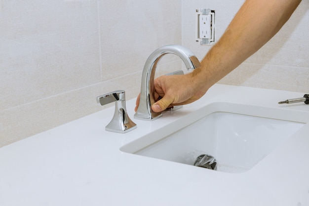 Klempner Hände bei der Arbeit im Badezimmer, Sanitär Reparatur Service der neue Wasserhahn ein Waschbecken