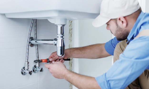 Klempnerhände reparieren Wasserhahn auf Hintergrund