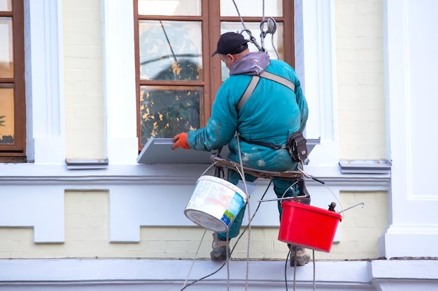 Kletterarbeiter hält ein Fenster und eine Fassade eines Wohngebäudes in der Industrie des Reparaturbaus instand