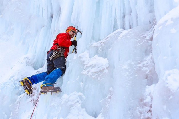 Kletterer mit zwei Eisgeräten stürmt die senkrechte Wand des Gletschers