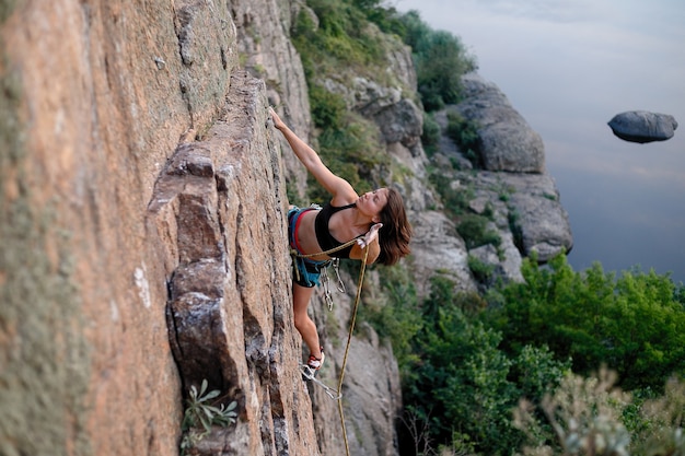Kletterer überwindet anspruchsvolle Kletterroute. Ein Mädchen klettert auf einen Felsen. Frau im Extremsport tätig. Extremes Hobby.
