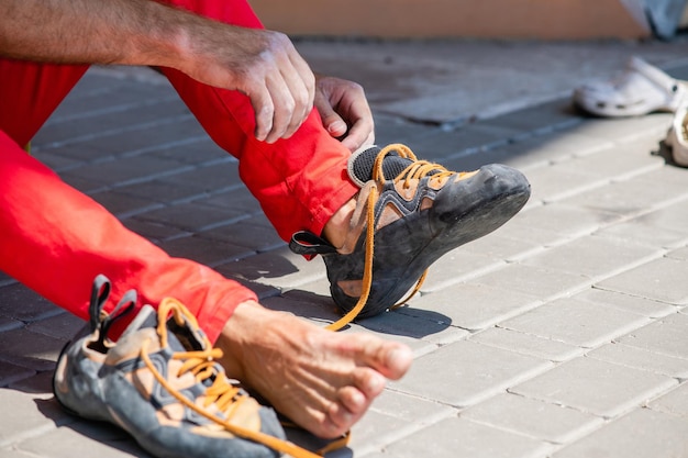 Kletterer zieht Kletterschuhe an und bindet Schnürsenkel Vorbereitung auf das Klettern Männliche Hände Nahaufnahme