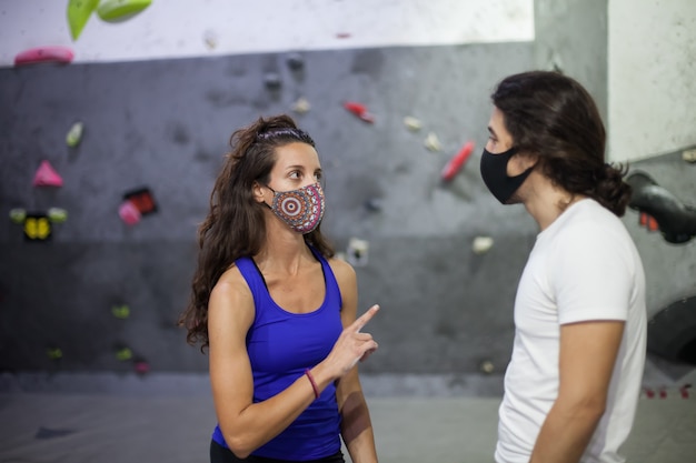 Kletterlehrer und Schüler tragen Maske auf steiler Felswand drinnen