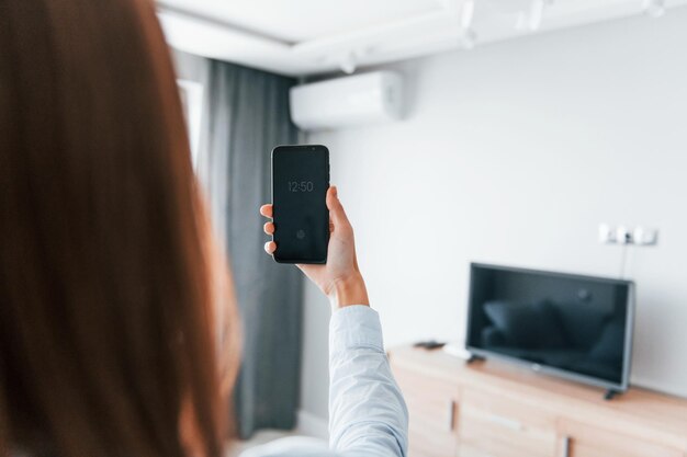 Klimaanlage per Tablet steuern Junge Frau ist tagsüber drinnen im Zimmer eines modernen Hauses