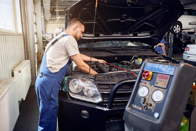 Klimaanlage tanken Ein Mechaniker pumpt bei einem Autoservice Freon in die Klimaanlage