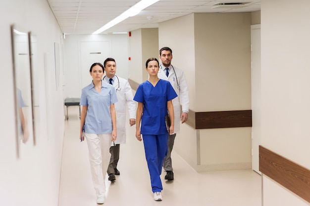 klinik, beruf, menschen, gesundheitswesen und medizinkonzept - gruppe von medizinern oder ärzten, die den krankenhauskorridor entlanggehen