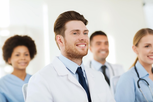 Klinik, Beruf, Menschen und Medizinkonzept - glücklicher männlicher Arzt über eine Gruppe von Medizinern, die sich im Krankenhaus treffen